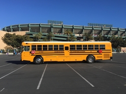 Rear Engine School bus parked next to a sports venue